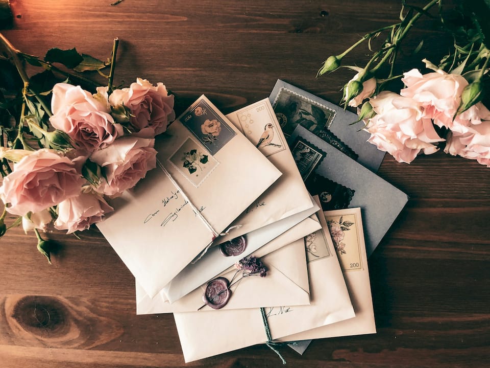 Letters to Mama envelopes with stamps and roses on a wooden table